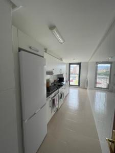 Una cocina blanca con refrigerador y estufa. en Casa acogedora golf Rioja alta, en Cirueña