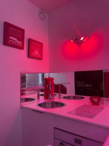 a pink room with three sinks and a red light at Ly'Ove in Lyon