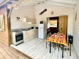 a kitchen with a table with chairs and a refrigerator at Bungalow cosy à Deshaies avec piscine in Deshaies
