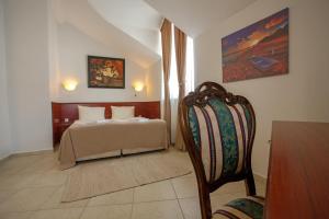 a hotel room with a bed and a chair at Hotel CENTRAL Balchik in Balchik +12 photos
