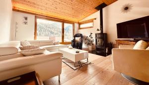 a living room with couches and a tv and a fireplace at Apartment Blick Schloss Tarasp - Arventraum mit Gartenspa in Scuol