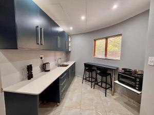 a kitchen with black cabinets and white counter tops at Pazuri Homestay in Kempton Park