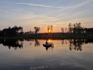 a person in a boat on a lake at sunset at Ekolandia in Tuszkowy +15 photos