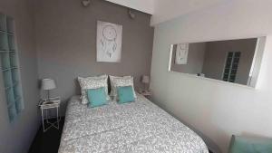 a bedroom with a bed with pillows and a mirror at Appartement Seignosse bord de plage in Seignosse