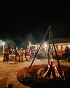 a group of people sitting around a fire at Pulse Desert Camp in Merzouga