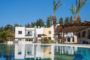 a swimming pool in front of a villa at SunNsea Apartment in Paphos