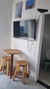 een tv aan een muur met twee tafels en twee krukken bij Quarto verde Asa Sul in Brasilia