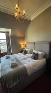 a bedroom with a large white bed with a chandelier at Brooklynn Guest House in Grantown on Spey