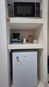 een magnetron op een plank boven een koelkast bij Quarto verde Asa Sul in Brasilia