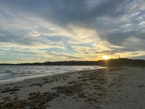 a beach with the sun setting in the distance at Casa Turmalina in Japaratinga