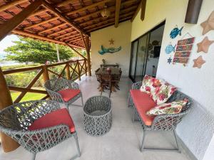 a porch with chairs and a table and a table at Casa Turmalina in Japaratinga