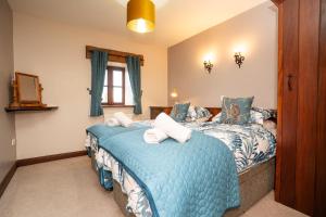 a bedroom with two beds with blue comforter at Ystumgwern Luxury Barn Conversions in Dyffryn