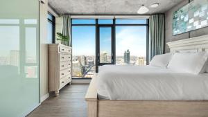 Un dormitorio con una cama blanca y una ventana grande. en Executive Sky LUX - 2 BD 2BA Views Pool Patio & Gym, en Calgary 25 fotos más