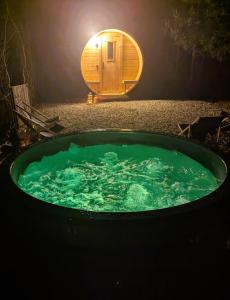 een ronde kuip met een hobbithuis op de achtergrond bij Forreset - leśny apartament, sauna i balia jacuzzi in Gietrzwałd