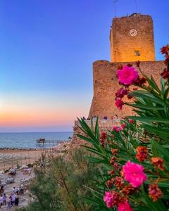 una torre dell'orologio accanto a una spiaggia con fiori rosa di Rio Mare a Termoli