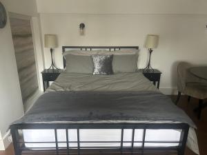 a bed in a bedroom with two lamps and a bedskirtspectspectspectspects at Spacious studio with free EV recharge overnight in Watford