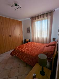 a bedroom with a bed with a red bedspread at Appartamento Sabina Rosignano Castiglioncello in Rosignano Solvay