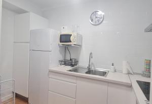 a white kitchen with a sink and a microwave at Apartamento Azul in Nerja +5 photos