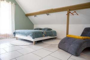 ein Schlafzimmer mit einem Bett und einem Stuhl in der Unterkunft Les gites Inclusifs d'OMAOMA in Saint-Jouin-Bruneval