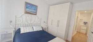 a white bedroom with a blue bed and white cabinets at Apartamento Azul in Nerja