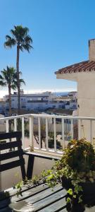 a bench sitting on a balcony with a palm tree at Apartamento Azul in Nerja