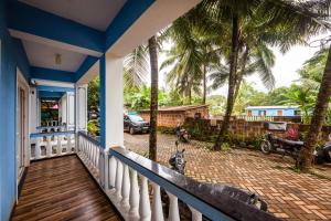 a porch of a house with palm trees at Susegad Shores - Chic 1BHK Coastal Escape in Siolim