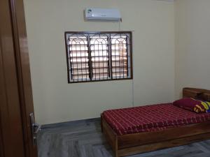 a bed in a room with a barred window at Charmante maison près de Cotonou in Cotonou