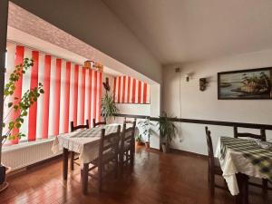 a dining room with a table and chairs and large windows at Pensiunea Dor de munte in Arefu