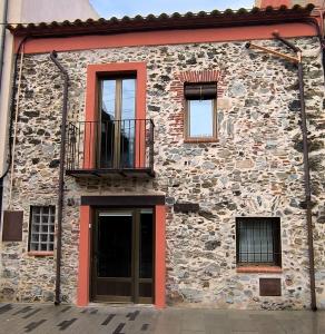 a stone building with a balcony and a door at Ca LA LIDIA GARRIGUELLA in Garriguella