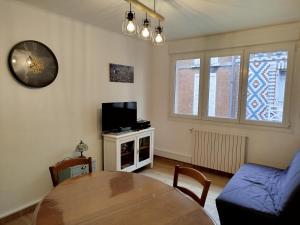 a living room with a table and a tv at la villa des bons enfants in Le Tréport