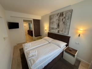 a bedroom with a large bed with a painting on the wall at San Carlo Luxury Apartments in Lugano