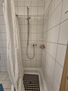 a shower in a white tiled bathroom with a shower curtain at Chambre cosy et chaleureuse chez Soso in Châtel-Saint-Denis +3 photos