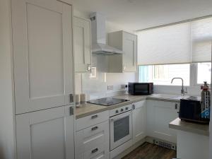 une cuisine blanche avec des armoires blanches et un évier dans l'établissement Beach Buoys holiday chalet Close to the dog friendly beach, à Bridlington