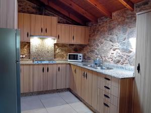 a kitchen with wooden cabinets and a sink and a microwave at Stone Cottage La COMPOSTELANA in Curtis