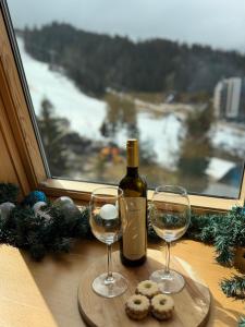 a bottle of wine and two glasses on a table at Blue Winter Heaven in Jahorina +5 photos
