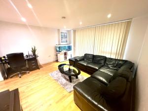 a living room with a black leather couch and a television at Colindale Apartments in Colindale