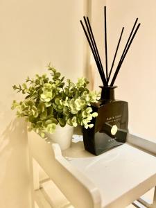 Una mesa con un jarrón negro con flores y palos. en Colindale Apartments, en Colindale