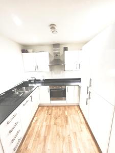 cocina con armarios blancos y suelo de madera en Colindale Apartments, en Colindale