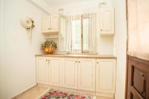 a kitchen with white cabinets and a window at OURANIAS HOUSE in Kalymnos +50 photos