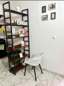 Una silla blanca junto a un estante de libros. en Home ADOK, en Abiyán