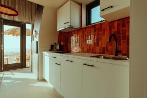 a kitchen with white cabinets and a view of the ocean at Venti Beach Houses in Zandvoort +4 photos