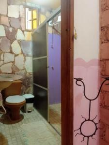 a bathroom with a toilet and a glass door at Pousada Casa De Helia in Lençóis
