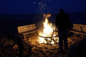 a man standing in front of a fire in the sand at Lakefront Cottages 4 & 5 - 6BR Retreat for 12 in Lincoln Junction