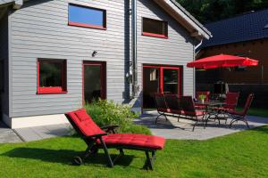 a patio with red chairs and a table and umbrella at Ferienhaus Jonas in Rieden