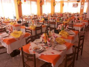 duża sala bankietowa ze stołami z pomarańczowymi i białymi ustawieniami w obiekcie Hotel Consul w mieście Cattolica
