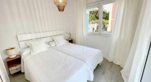 Un dormitorio blanco con una cama blanca y una ventana. en Villa Turquesa B, en Viveiro