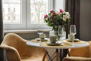 a table with a vase of flowers and wine glasses at Alpari Wawel in Kraków