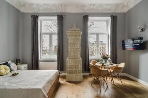 a bedroom with a bed and a table and two windows at Alpari Wawel in Kraków