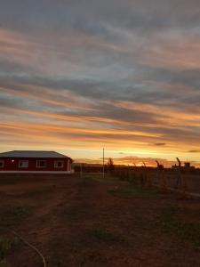 a barn in a field with a sunset in the background at Depto Muy Patagónico, lindo y cómodo in Trelew