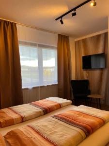 two beds in a hotel room with a window at Weingut Lindenhof in Thörnich